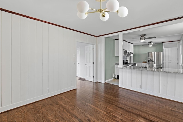 unfurnished living room featuring crown molding, a sink, ceiling fan with notable chandelier, baseboards, and dark wood-style floors