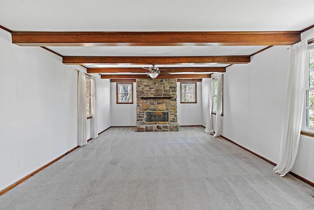 unfurnished living room with light colored carpet, beam ceiling, a fireplace, a ceiling fan, and baseboards