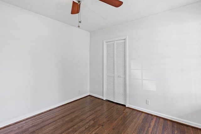 unfurnished bedroom with a closet, ornamental molding, dark wood-style flooring, baseboards, and a ceiling fan