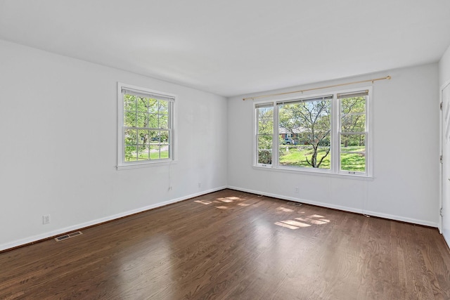 spare room with baseboards, visible vents, and wood finished floors