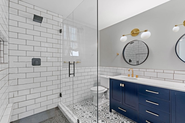 bathroom featuring vanity, toilet, tile walls, tile patterned floors, and a tile shower