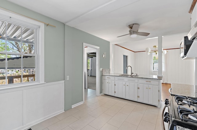 kitchen with white cabinets, a sink, a ceiling fan, light tile patterned floors, and gas range
