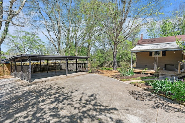 view of parking with fence, driveway, and a carport