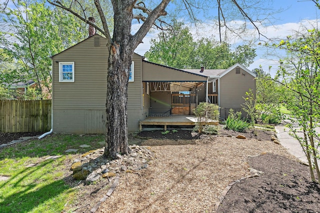 back of house with fence, a chimney, and a deck