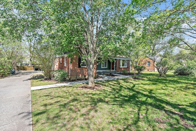 obstructed view of property featuring brick siding and a front lawn