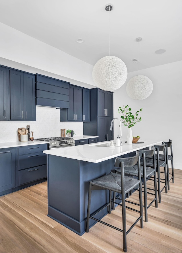 kitchen with a breakfast bar area, hanging light fixtures, light countertops, light wood finished floors, and wall chimney exhaust hood