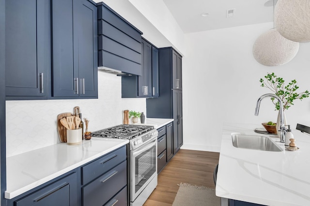 kitchen featuring stainless steel gas stove, extractor fan, dark wood-type flooring, a sink, and backsplash