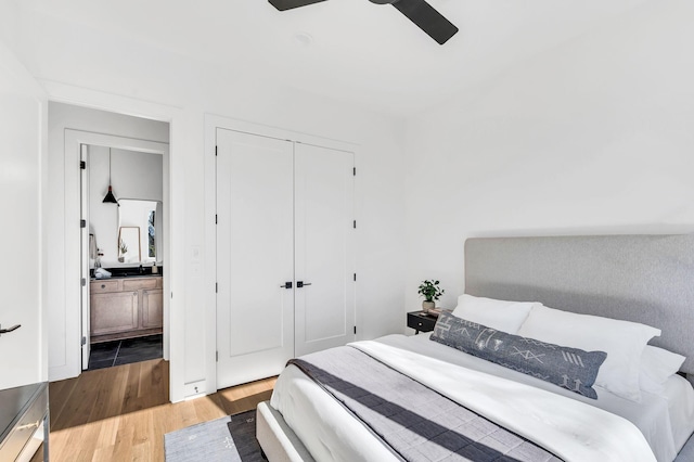 bedroom with connected bathroom, a ceiling fan, wood finished floors, and a closet