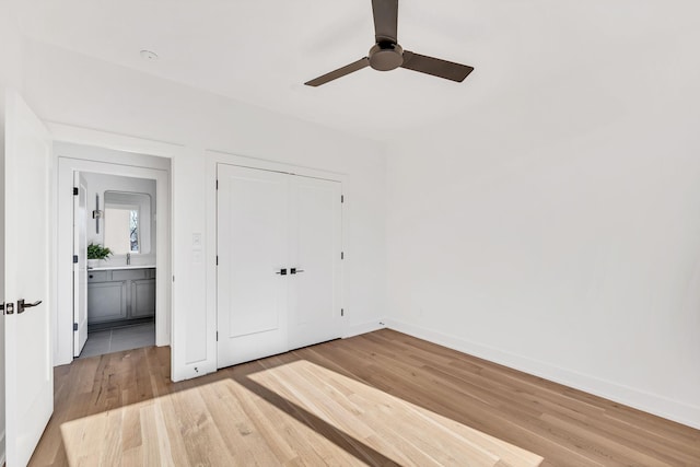 unfurnished bedroom with baseboards, a ceiling fan, a closet, and light wood-style flooring
