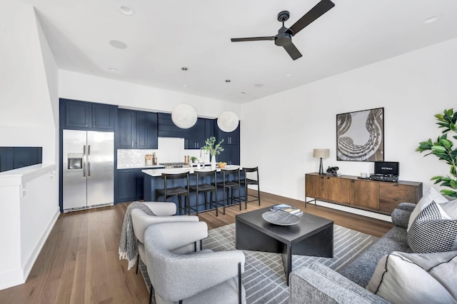 living area featuring baseboards, ceiling fan, and dark wood-type flooring