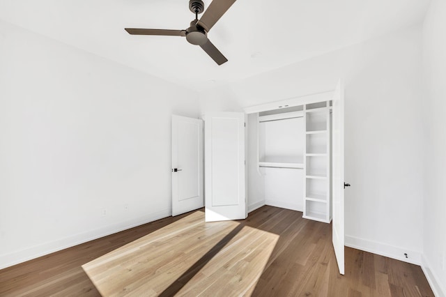 unfurnished bedroom featuring a closet, baseboards, a ceiling fan, and wood finished floors