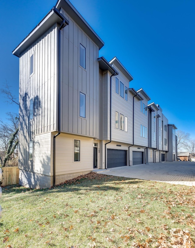 exterior space featuring a garage, fence, board and batten siding, and a front lawn