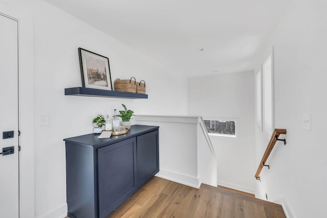 interior space with light wood-type flooring, baseboards, and an upstairs landing