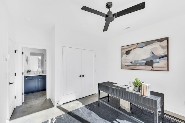 office space featuring visible vents, finished concrete flooring, baseboards, ceiling fan, and a sink