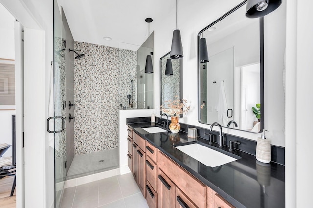 bathroom featuring double vanity, a shower stall, a sink, and tile patterned flooring