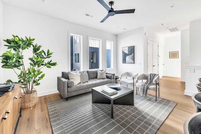 living room featuring baseboards, a ceiling fan, wood finished floors, and visible vents