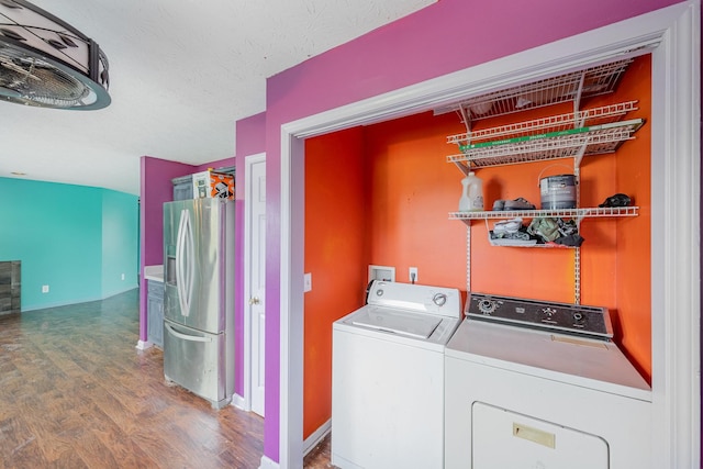 washroom with washing machine and clothes dryer, laundry area, and wood finished floors