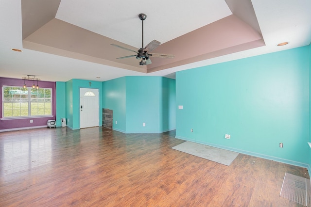 spare room with baseboards, a tray ceiling, and wood finished floors