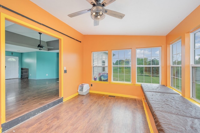 unfurnished sunroom with baseboards, vaulted ceiling, wood finished floors, and visible vents
