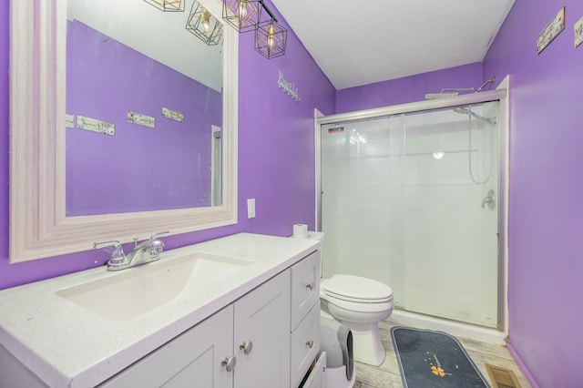 bathroom featuring vanity, toilet, a textured ceiling, a shower stall, and visible vents