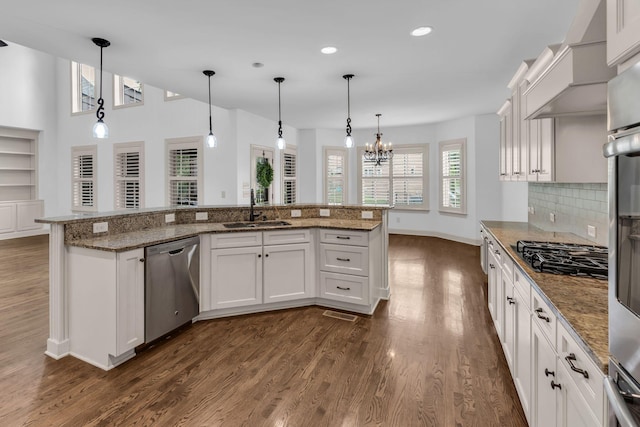 kitchen featuring dark wood finished floors, dishwasher, a sink, baseboards, and black gas stovetop