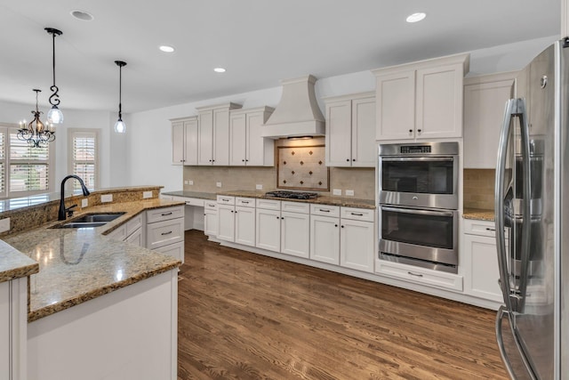 kitchen featuring dark wood finished floors, a sink, premium range hood, stainless steel appliances, and recessed lighting