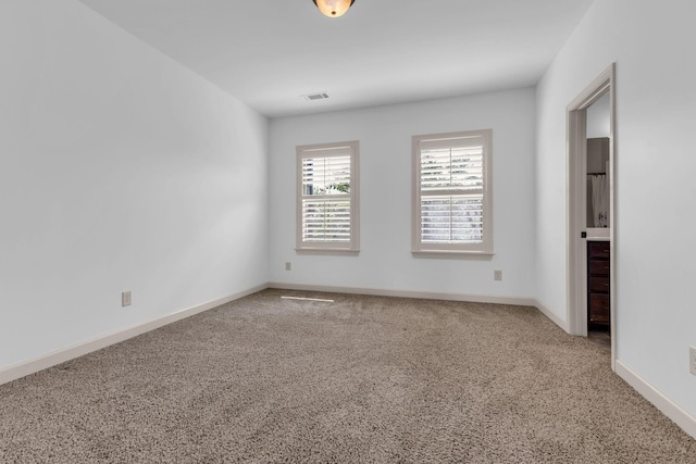 carpeted empty room featuring baseboards and visible vents