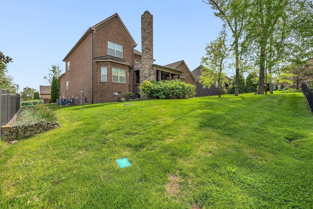back of property with brick siding, a lawn, fence, and a chimney