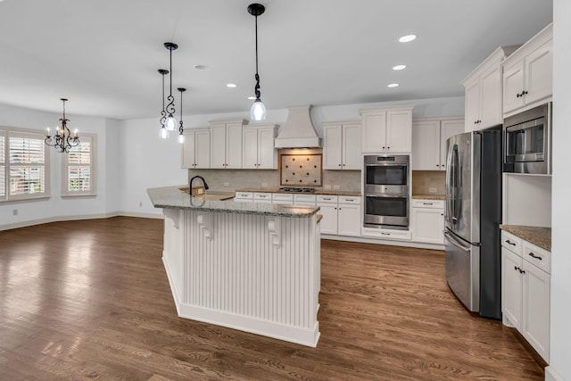 kitchen featuring decorative backsplash, appliances with stainless steel finishes, a sink, premium range hood, and recessed lighting