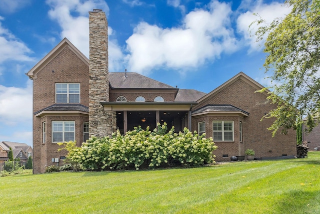 rear view of property featuring brick siding, crawl space, a yard, and a chimney