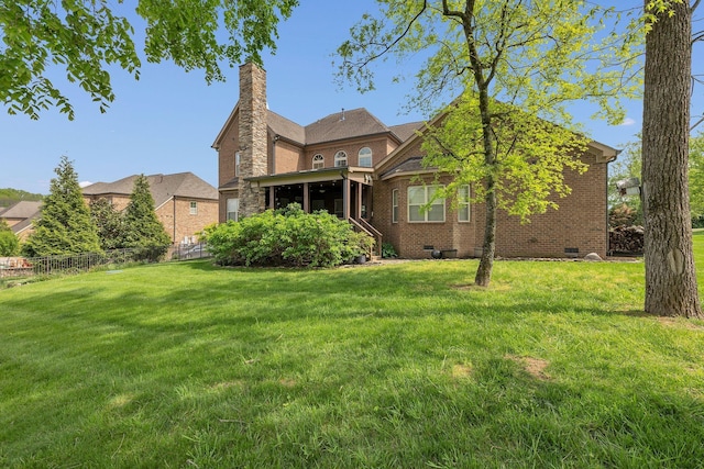 back of house featuring fence, a yard, and brick siding