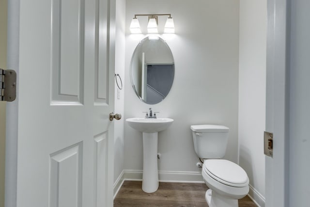 bathroom featuring toilet, baseboards, a sink, and wood finished floors
