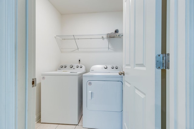 laundry room with light tile patterned floors, separate washer and dryer, and laundry area