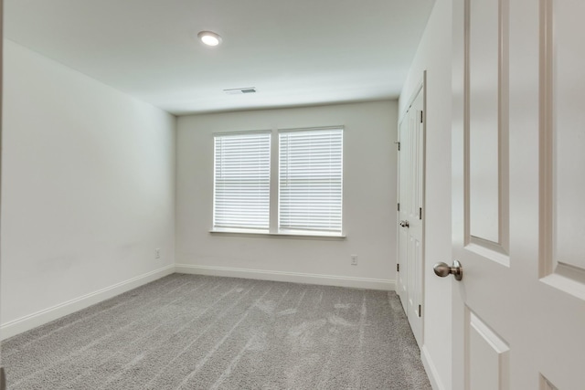 carpeted spare room featuring baseboards and visible vents