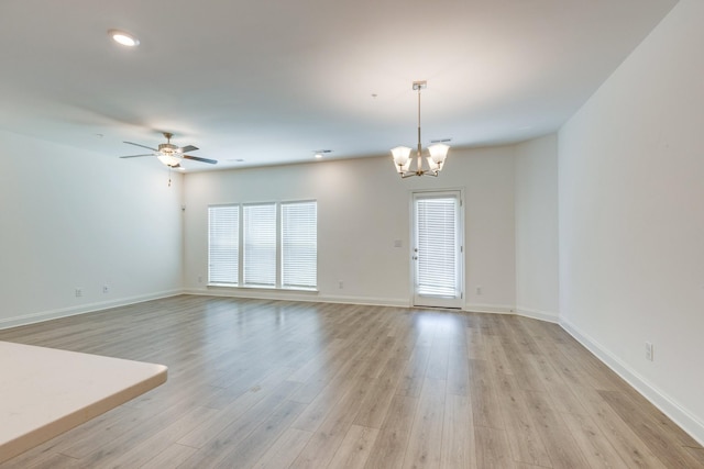 unfurnished living room with recessed lighting, baseboards, ceiling fan with notable chandelier, and light wood-type flooring