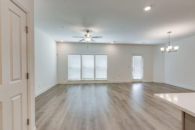 unfurnished living room with recessed lighting, baseboards, light wood-style flooring, and ceiling fan with notable chandelier