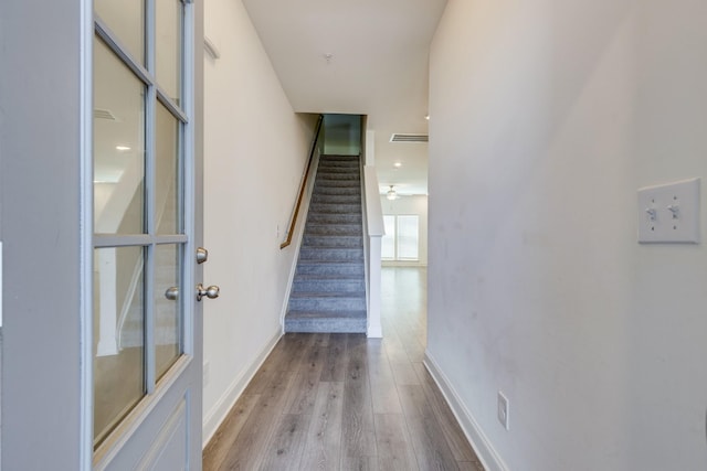stairs featuring baseboards, wood finished floors, and visible vents