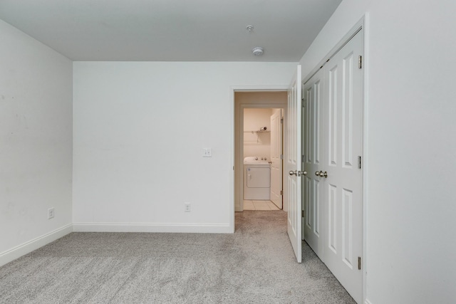 unfurnished bedroom featuring baseboards, light carpet, a closet, and washer and clothes dryer