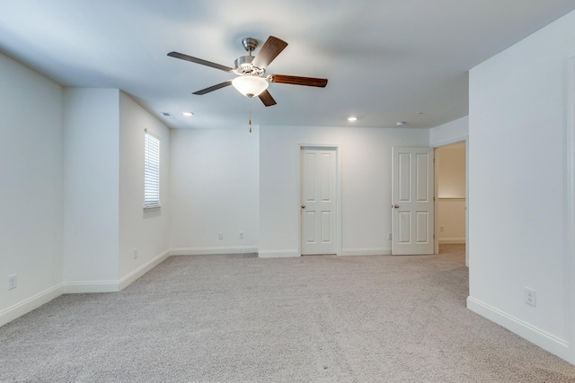 empty room featuring baseboards, ceiling fan, and light carpet