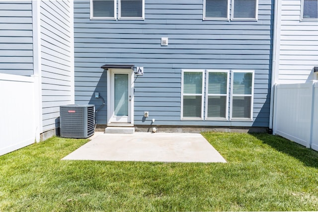 doorway to property with central air condition unit, a patio, and a lawn