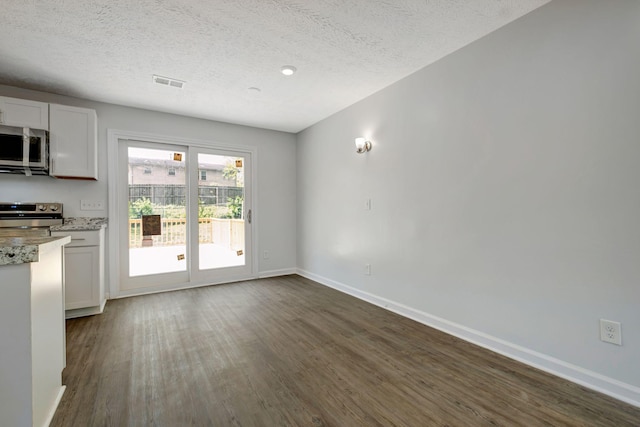 217 Sterry Ct, Antioch, TN 37013 - unfurnished dining area with dark wood-style flooring, a textured ceiling, visible vents, and baseboards