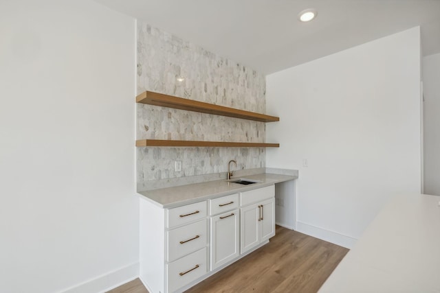 bar with decorative backsplash, baseboards, light wood-type flooring, recessed lighting, and a sink