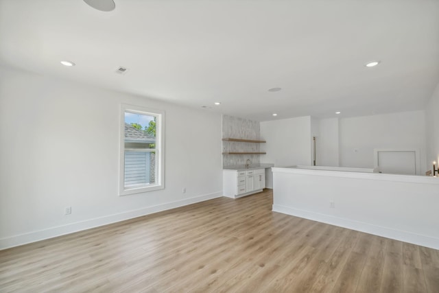 unfurnished living room with recessed lighting, baseboards, and light wood-style floors
