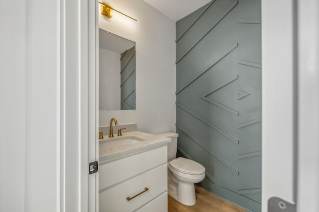half bath featuring vanity, wood finished floors, and toilet