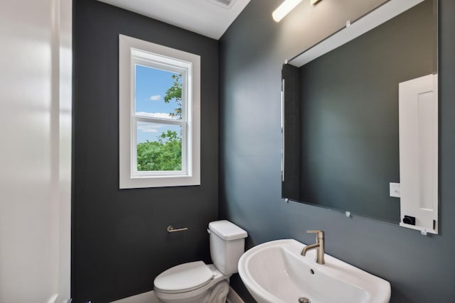 half bath featuring visible vents, a sink, a wealth of natural light, and toilet