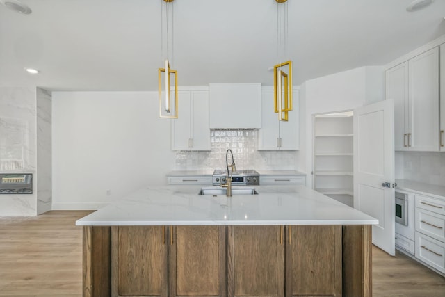 kitchen with white cabinetry, hanging light fixtures, decorative backsplash, and light wood-style floors