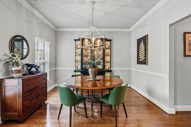 dining room with baseboards, a notable chandelier, ornamental molding, and wood finished floors