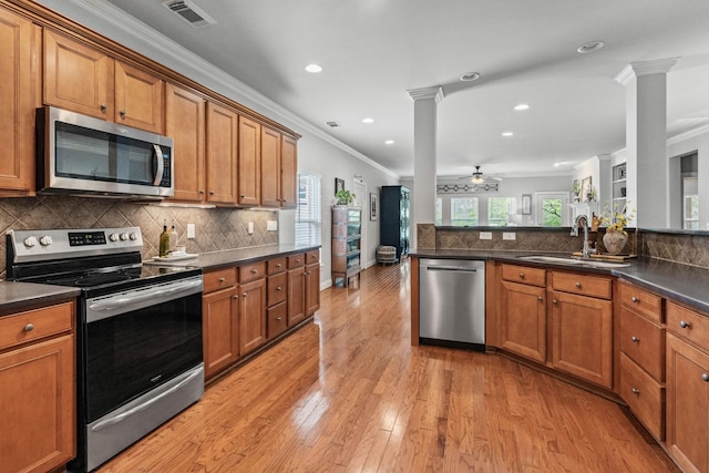 kitchen with ornate columns, a sink, appliances with stainless steel finishes, and brown cabinets