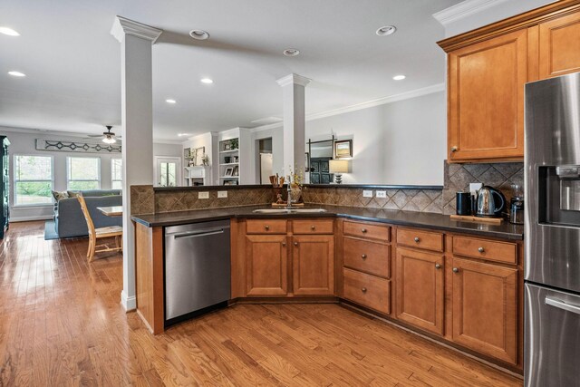kitchen featuring crown molding, brown cabinets, a sink, stainless steel appliances, and ornate columns