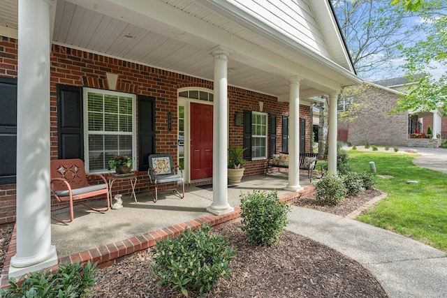 doorway to property with a porch and brick siding